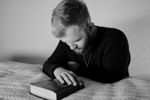 grayscale photo of a bearded man praying