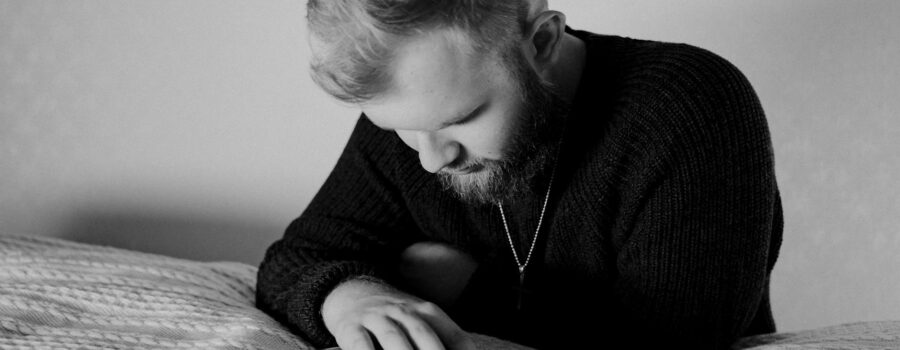 grayscale photo of a bearded man praying