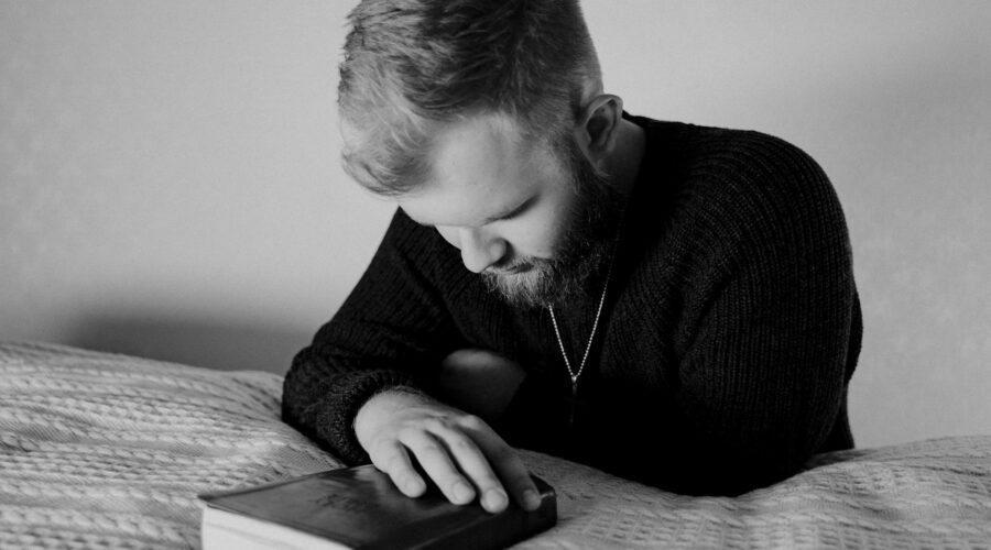 grayscale photo of a bearded man praying