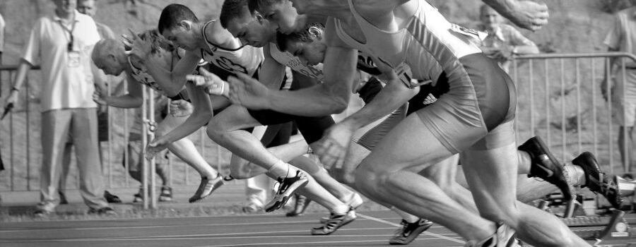 athletes running on track and field oval in grayscale photography